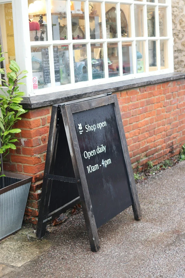 Real outdoor A-frame shop sign showing Open daily and 10am - 4pm