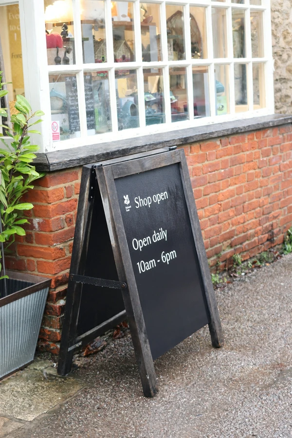 Actual AI-edited outdoor shop sign with opening hours changed to 10am - 6pm